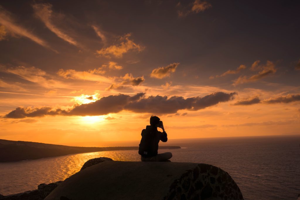 Un homme aimant voyager autour du monde admire le coucher du soleil propice à la méditation